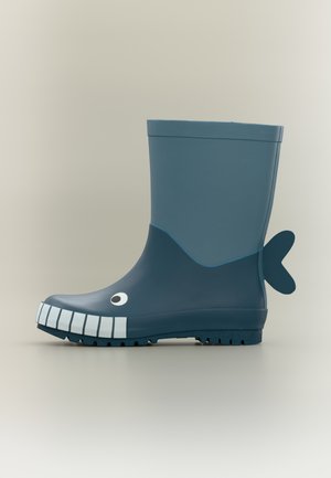 Μπλε λαστιχένια μπότα βροχής με σχέδιο φάλαινας, που διαθέτει χαμογελαστό πρόσωπο, μοτίβο λευκών δοντιών και μικρή μπλε ουρά στο τακούνι.