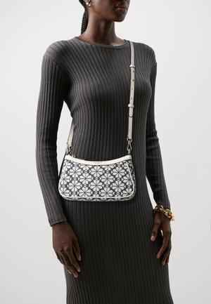 Crossbody bag featuring a floral pattern in navy and white, with a curved shape, smooth leather trim, and an adjustable strap.