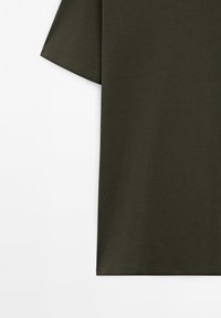 Dunkelolivgrünes Baumwoll-T-Shirt mit kurzen Ärmeln, einfachem geradem Saum und sichtbarer Naht an Ärmel- und unteren Kanten.