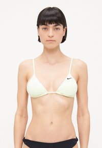 Svetložltý trojuholníkový bikiny top s tenkými ramienkami, zhromaždenou látkou a čiernym logom Nike na ľavej strane. Kontrastné čierne spodky.