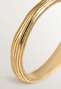 Anillo de oro con un acabado pulido, que presenta un diseño texturizado de tres líneas elevadas a lo largo de la superficie, con una banda interior suave.