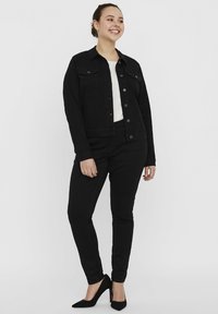 Mustmust denim jakk musta, nupuvääramisega, kahe rinnaeelise taskuga, koos mustade kitsaste pükstega ja mustade terava ninaga kontsakingadega. All on valge topp.