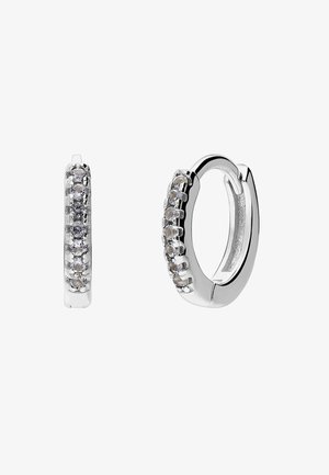 Boucles d'oreilles créoles en argent avec une rangée de petites pierres précieuses claires serties le long du bord extérieur, présentées sur un fond blanc.