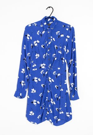 Niebieska sukienka na długi rękaw z guzikami, białym kwiatowym nadrukiem, kołnierzykiem i marszczeniem w talii, wisząca na czarnym wieszaku.