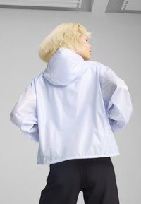 Veste à capuche bleu clair en matériau léger, avec des manches longues, une coupe décontractée et un design sobre sans motifs visibles.