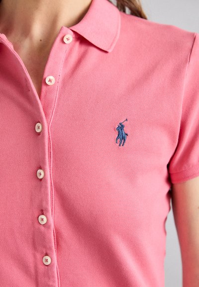 Rosa Poloshirt aus strukturiertem Stoff, mit Kragen, Knopfverschluss und einem blauen gestickten Logo auf der Brust.