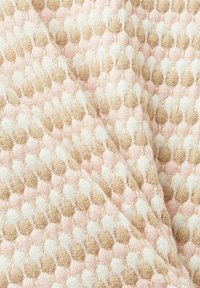 Tissu tricoté avec un motif nid d'abeille dans des tons beige, blanc et rose clair, plié pour montrer la texture et la profondeur.