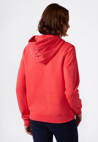 Sudadera de color coral con capucha con cordón, puños y dobladillo acanalados. Tejido suave, con un diseño simple sin gráficos ni patrones visibles.