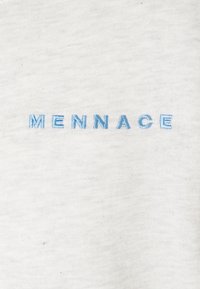Blå broderade bokstäver som stavar "MENNACE" på en ljusgrå texturerad tygbakgrund.