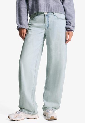 Light blue wide-leg jeans in denim fabric, featuring a button closure and front pockets. Paired with white sneakers. Simple, casual design.