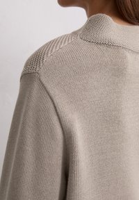 Beige Strickpullover mit einem strukturierten Schulterdesign. Verfügt über einen glatten Körper und sichtbare Nähte; leicht und lässig in der Optik.