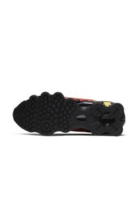 Black athletic shoe sole with a textured pattern. Features multi-colored accents and a distinctive round section at the heel.