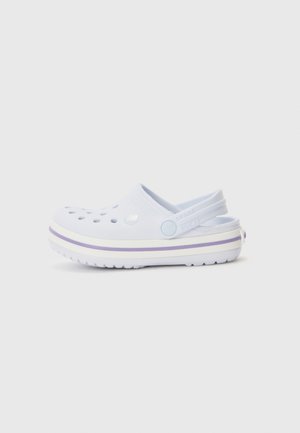 Zueco blanco sin cordones con empeine perforado, tira ajustable en el talón y suela gruesa con rayas moradas.