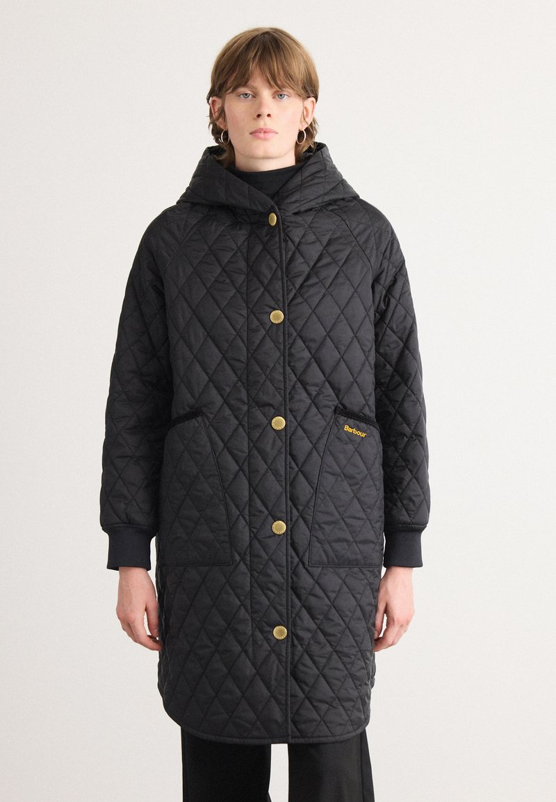 Manteau long matelassé noir avec une capuche, doté de fermetures à boutons dorés, de poches latérales et d'un logo subtil sur la poche. Texture lisse.