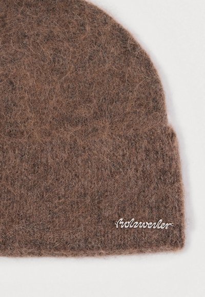 Ruda vilnonė kepurė su švelnia, pūkuota tekstūra. Yra sulenkta kraštinė ir metalinis logotipo ženkliukas, pritvirtintas šone.