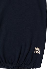 Tissu bleu marine foncé avec un bord élastique froncé et un petit texte beige "MIND STEADY" imprimé près du coin inférieur droit.