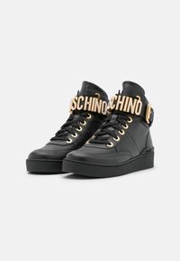 Svarta högskurna sneakers med guldöglor, svarta snörningar och guldprydda "MOSCHINO"-remmar framtill.