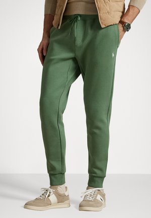 Pantaloni jogger din bumbac verde, cu talie elastică și mansete, având buzunare laterale și un mic logo pe coapsa stângă.