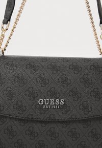 Borsa a tracolla nera con texture, caratterizzata da una finitura liscia, con logo in tono argento e dettagli a catena. Design compatto con chiusura a patta.