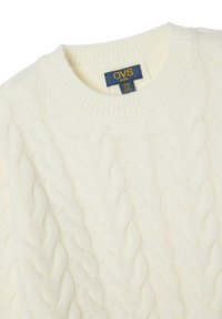 Cremefarbener gestrickter Pullover mit Zopfmuster und rundem Hals. Verfügt über ein Stoffetikett mit "OVS kids" in Blau und Gelb.