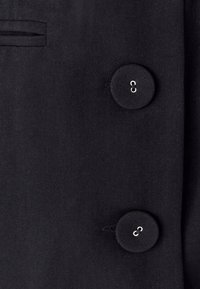 Czarny żakiet z gładkiego materiału, z dwoma okrągłymi guzikami i małym detalem kieszonki.