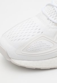 Vitaid sportskor med ett andningsbart mesh-övre med texturerade mönster, en slät tåhatt och en texturerad gummisula för bra grepp.