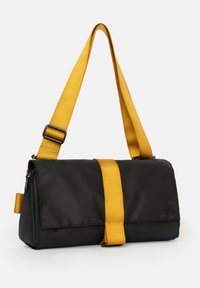 Borsa messenger nera con una tracolla regolabile gialla e dettagli in giallo. Presenta una chiusura con zip e un design con pattina piegata. Realizzata in tessuto liscio.
