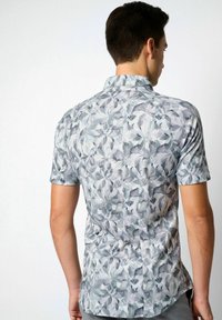 Kurzarmhemd aus leichtem Stoff mit einem grauen und grünen Blättermuster, klassischem Kragen und einer taillierten Rückenpartie.