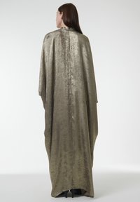 Longue cape métallique vert olive avec une texture lisse, un design minimaliste et un col haut, tombant librement jusqu'au sol.