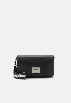 Sac en cuir noir porté en bandoulière avec une fermeture à verrou en argent et une sangle à motif avec le mot "dior" en blanc.