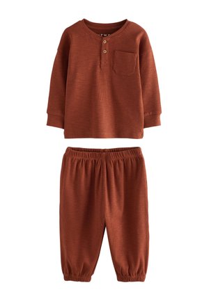Rust-colored long-sleeve shirt with three-button placket and front pocket, paired with matching elastic-waist pants, ribbed texture.
