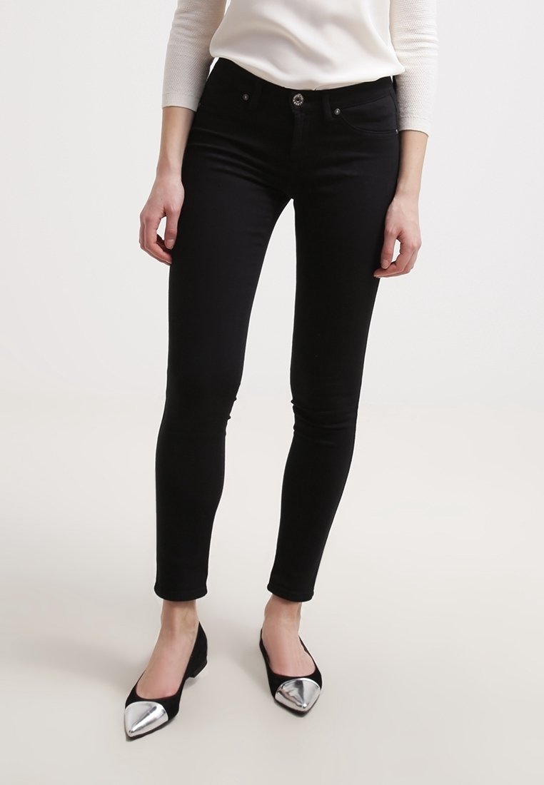 Černé skinny džíny s hladkou texturou a přiléhavým střihem, které mají přední zapínání na knoflík a pět kapsových stylů. V kombinaci s černými plochými botami.