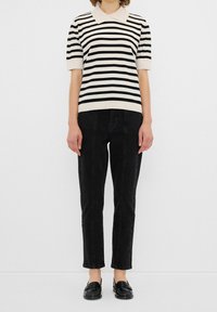 Mustat ja valkoiset raidoitetut lyhythihaiset puserot, joissa on kaulus, yhdistettynä slim-fit mustiin housuihin ja mustiin loafer-kenkiin. Pehmeä rakenne, rento tyyli.