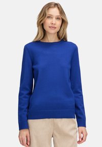 Kék, hosszú ujjú pulóver, puha kötött anyagból készült. Kerek nyakkivágással és bordás mandzsettával, valamint alsó résszel rendelkezik, lazán illeszkedve.