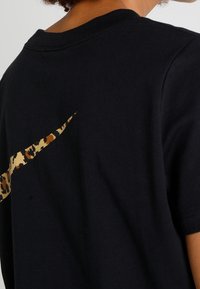 T-shirt in cotone nero con logo Nike a stampa leopardata sul retro, design classico con collo a giro e maniche corte.