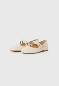 Patent cream ballet flats featuring two elastic straps, rounded toe, and small heel with decorative button accents on the side.