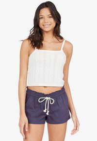 Un crop top en tricot blanc avec un motif chevron texturé, associé à un short bleu marine avec cordon de serrage, offrant une coupe décontractée et une taille élastique.