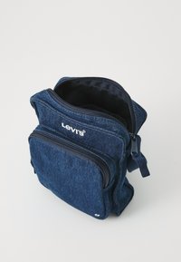 Traper torba plave boje s dva odvojena pretinca na zatvarač, s gornjom drškom i Levi's logotipom sprijeda. Teksturirana tkanina s čvrstim zatvaračima.