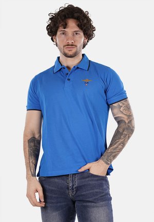Polo shirt blu con colletto, maniche corte e logo ricamato sul petto. Realizzato in un tessuto liscio con una forma aderente.
