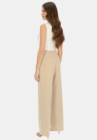 Dopasowana biała bluzka w zestawie z beżowymi spodniami o wysokim stanie i szerokich nogawkach. Gładki materiał o miękkiej teksturze, charakteryzujący się prostym designem i minimalną ilością szwów.