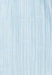 Hellblaue, strukturierte Stoffbahn mit vertikalen Falten und horizontalen, gerafften Nähten. Das Material wirkt weich und leicht, geeignet für Kleidungsstücke.