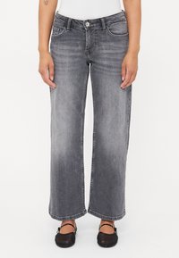 Bredbenta grå denimjeans med en lätt urblekt yta, med framfickor och knappstängning. Stylade med svarta flats.