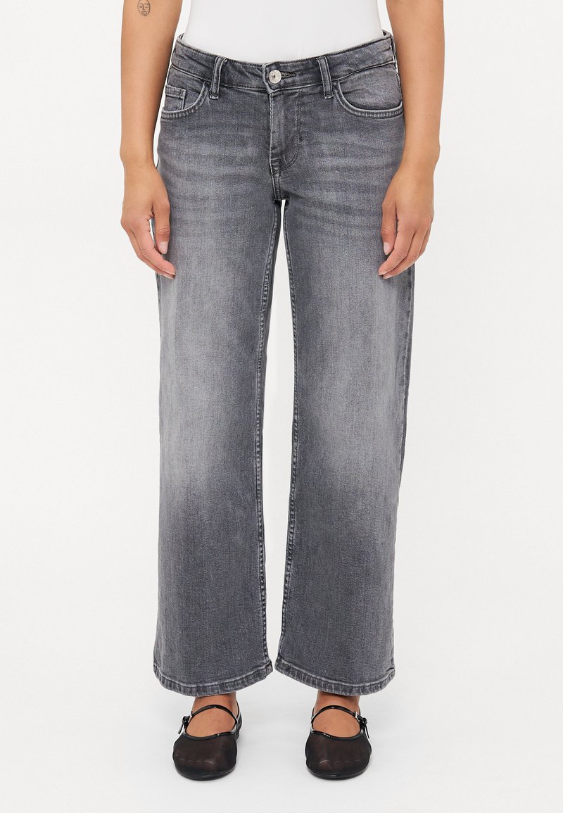 Bredbenta grå denimjeans med en lätt urblekt yta, med framfickor och knappstängning. Stylade med svarta flats.