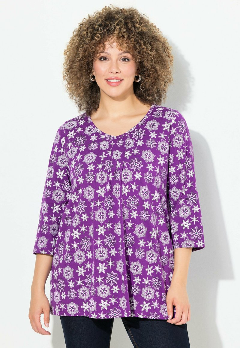 Tunic floreale viola con scollo a V, caratterizzata da maniche a tre quarti e una vestibilità ampia, decorata con intricati motivi floreali bianchi.