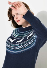 Maglione blu navy con un colletto a motivo circolare che presenta motivi di animali bianchi. Realizzato in un tessuto morbido con polsini a coste e design dettagliati.