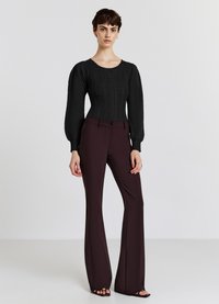 Maglione nero a maglia con maniche a palloncino, abbinato a pantaloni a vita alta in bordeaux scuro a zampa d'elefante. Design minimalista, texture liscia.