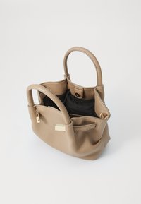 Beige leather handbag with two round handles, a textured surface, and an open top revealing a black fabric lining and a side zip pocket.