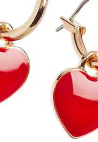 Orecchini a cerchio dorati con charm a forma di cuore rosso lucido. I cuori sono lisci con una finitura brillante, attaccati da piccoli connettori dorati.