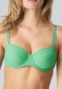 Groene beha van een gladde stof, met onderdraadondersteuning en geschulpte bandaccenten. Bevat een centrale decoratieve knop en naadloze cups.