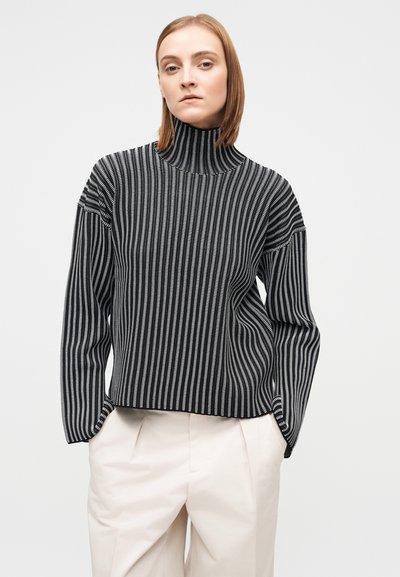 Μπλούζα ζιβάγκο με μαύρες και άσπρες ρίγες, μακρυμάνικη, με χαλαρή εφαρμογή και ριμπ υφή. Συνδυάζεται με ανοιχτόχρωμο παντελόνι.